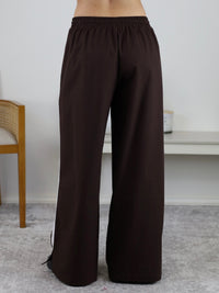 Rear view of the Urban Wide Leg Side Stripe Linen Track Pant in dark brown, featuring a wide-leg fit, white vertical side stripe, and elasticated waistband.