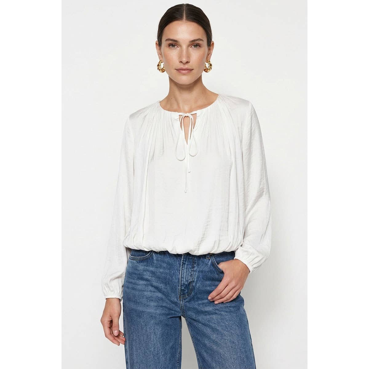 A wine-colored Naked Zebra - Long Sleeve Draped Bubble Hem Blouse with a keyhole neckline, tie closure, and gathered bubble hem, worn with blue jeans.
