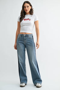 A woman wearing a white crop top with red prints and JBD - Mid Rise Sleek Tuxedo Sweat Pants in medium denim (DP914: 24) stands against a plain white background.