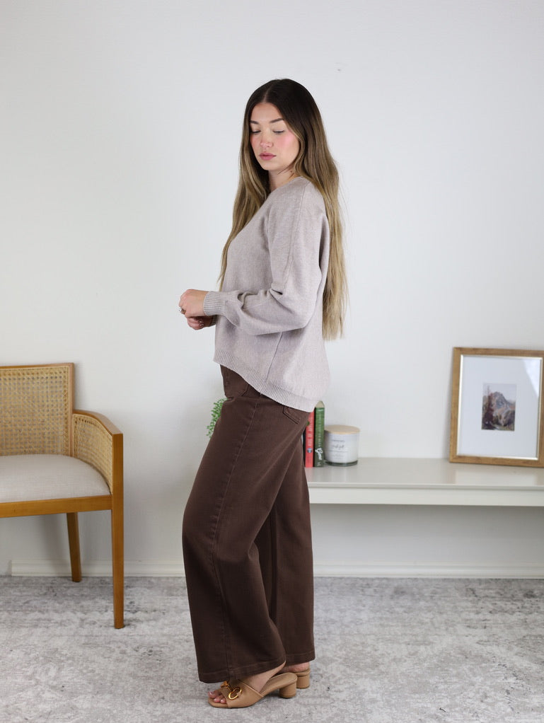 A person wearing a beige Eli Front Seam Sweater with a vertical front seam and brown wide-leg pants.