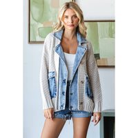 A woman stands indoors in the Veveret - Knit Body Denim Layerd Jacket: Cream / Denim / L over a white top and denim shorts, her expression neutral. An abstract painting hangs on the wall behind her.