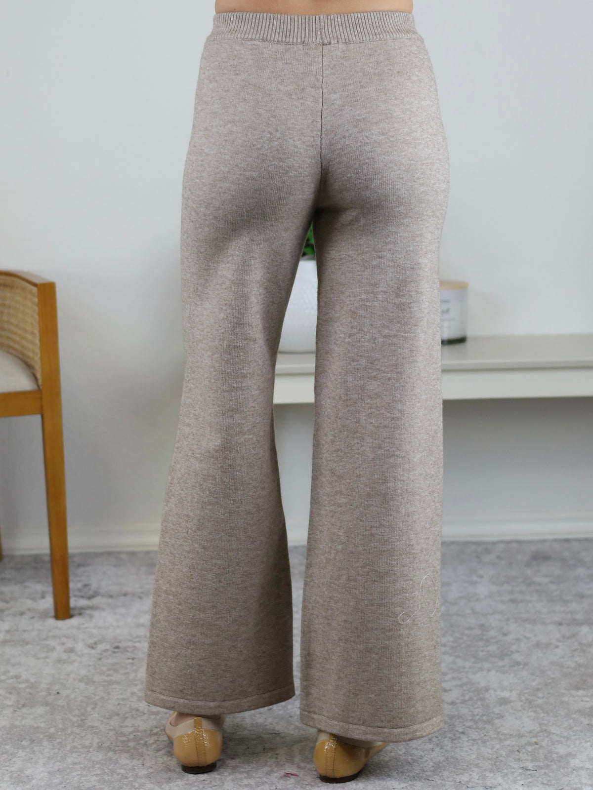 A person wearing the Rebecca Sweater/Pant Set, featuring high-waisted, wide-leg beige knit trousers paired with beige low-heeled shoes.