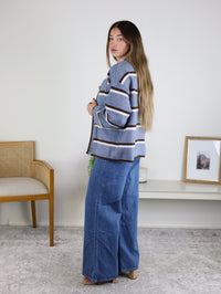 A person wearing a blue, white, and brown Nora Stripe Button Down Knit Cardigan and wide-leg blue jeans.