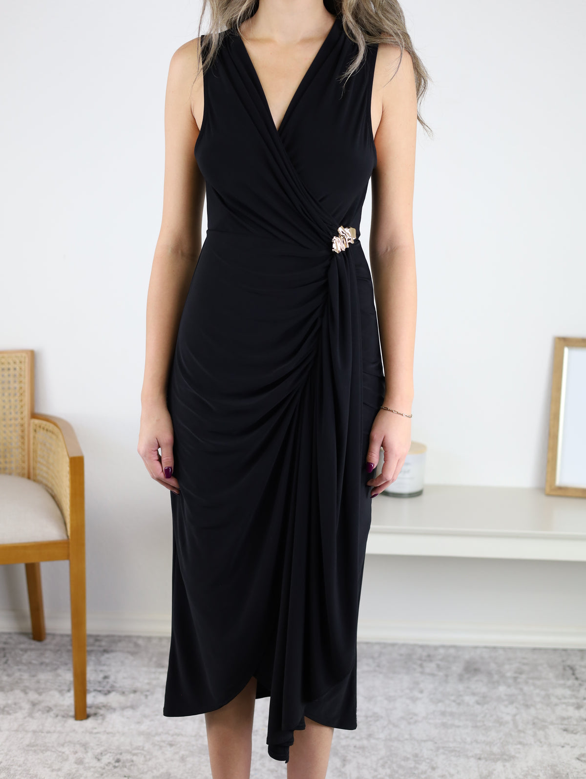 Sleeveless black Kamden Side Gather midi dress with a V-neckline, gathered waist detail, and a decorative gold brooch at the side.