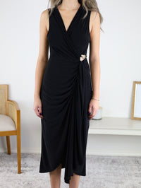 Sleeveless black Kamden Side Gather midi dress with a V-neckline, gathered waist detail, and a decorative gold brooch at the side.