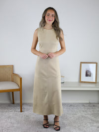 A woman wearing a tan sleeveless Cole Suede A-Line Maxi Dress and black strappy heels.