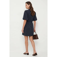 A woman wears a Naked Zebra - Puff Sleeve Cinched Waist Mini Dress: Navy / L, styled with a dark brown handbag and heeled sandals.
