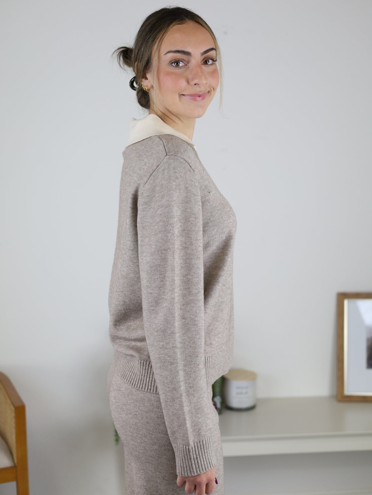 A person wearing the beige Rebecca Sweater/Pant Set, featuring a long-sleeved sweater with a contrasting collar and matching knit pants.