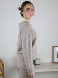 A person wearing the beige Rebecca Sweater/Pant Set, featuring a long-sleeved sweater with a contrasting collar and matching knit pants.