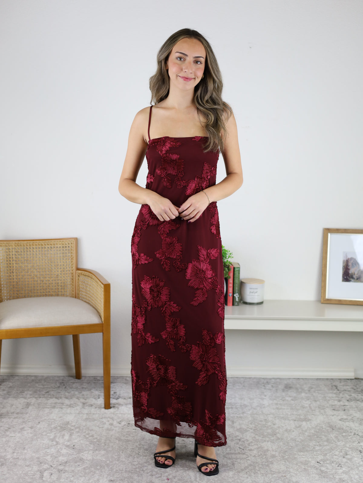 A woman wearing the Axel Applique Mesh Maxi Dress, a romantic, floor-length burgundy gown with a sheer overlay and floral appliqué embroidery.