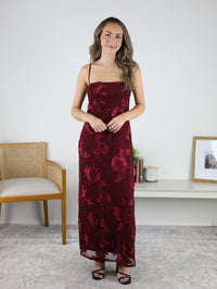 A woman wearing the Axel Applique Mesh Maxi Dress, a romantic, floor-length burgundy gown with a sheer overlay and floral appliqué embroidery.