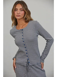 A woman with long brown hair wears the Creamon - CTP3592 BROWN Lounge Striped Button Down Top & Pants Set in Brown Stripe, featuring a long-sleeve button down top with blue buttons and a drawstring waist, paired with matching wide leg pants, as she stands against a plain background.