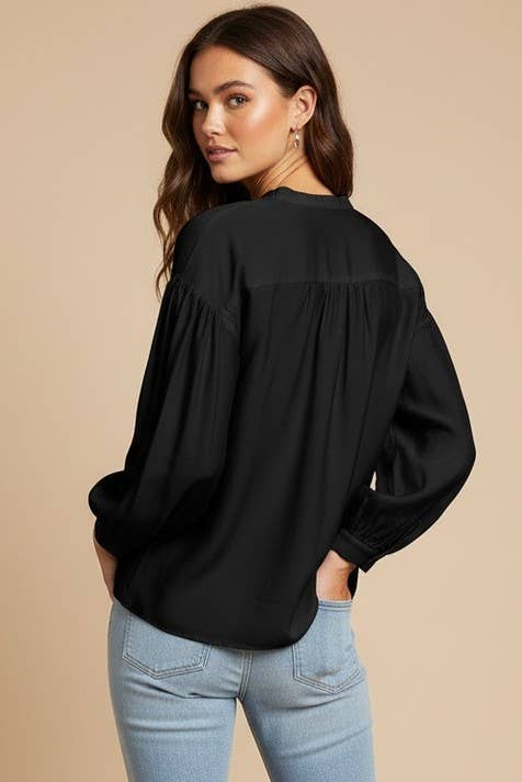 A woman seen from the back wearing a Naked Zebra - Button-down Blouse With Gathered Neckline: Black / L, an elegant black button-down blouse with a gathered neckline.