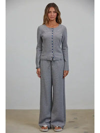 A woman stands against a plain background wearing the Creamon - CTP3592 BROWN Lounge Striped Button Down Top & Pants Set in brown stripe, paired with white sandals.