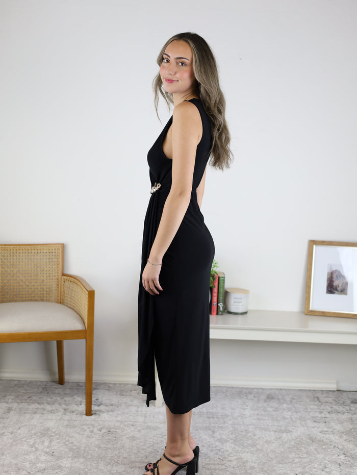 A woman in profile wears a black Kamden Side Gather Midi Dress, featuring a V-neck, side gathering, and a decorative waist accent.