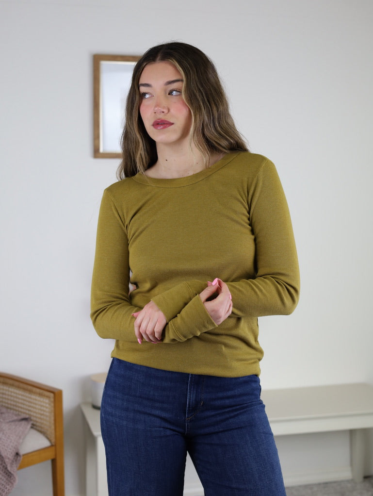 Woman wearing a long-sleeved olive green Dee Ribbed Round Neck Tee and dark blue jeans.