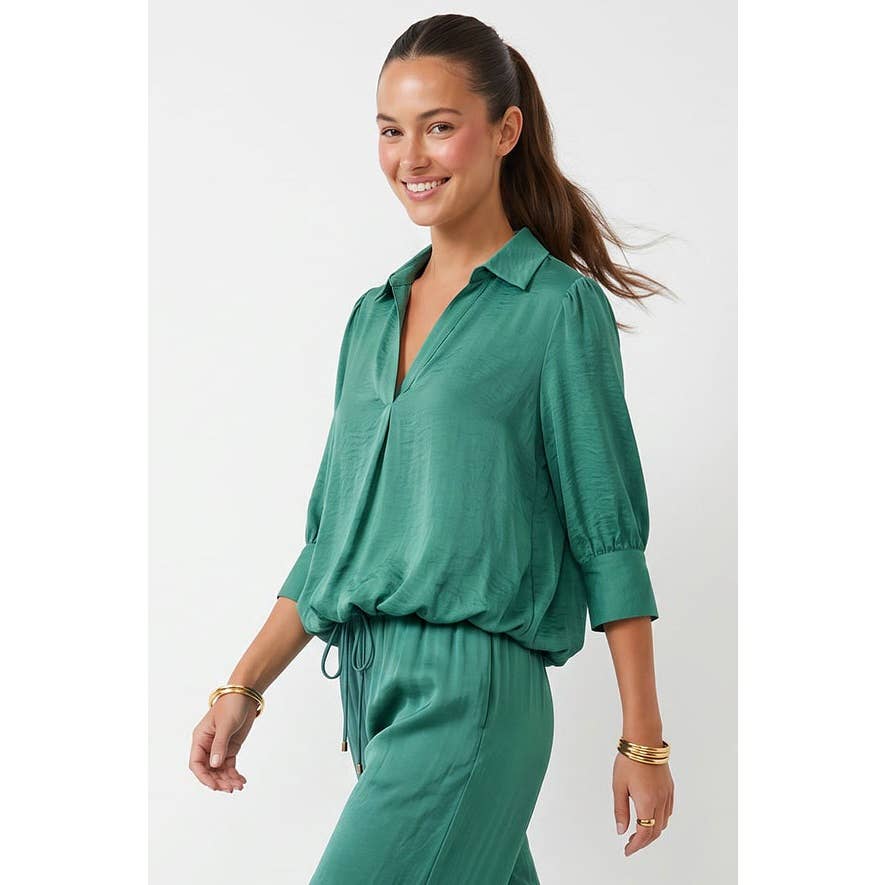 A woman wearing a Naked Zebra - Half Sleeve Hi-lo Bubble Hem Blouse in wine, featuring a green collared half-sleeve design with a bubble hem.