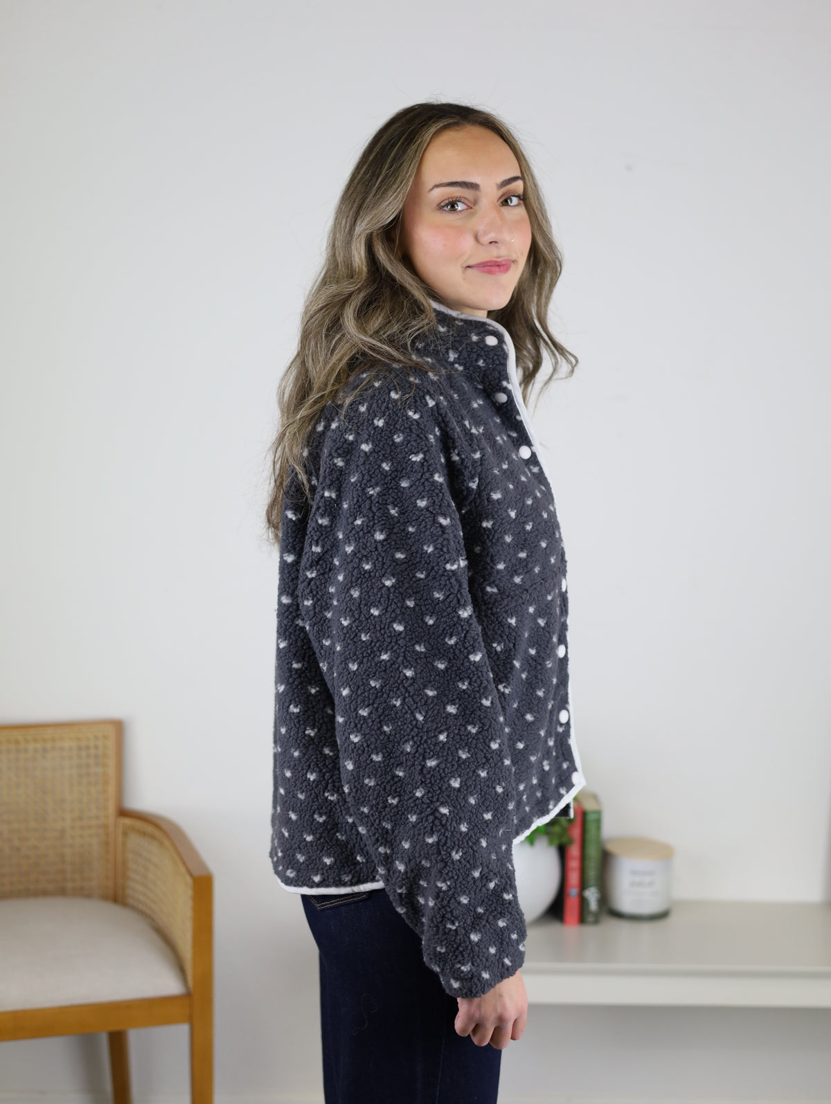 A woman wears a grey, high-pile Reba Fleece Puffer Jacket button-down patterned with small white hearts.