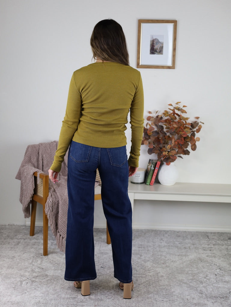 Woman seen from the back wearing the olive green Dee Ribbed Round Neck Tee with wide-leg blue jeans.