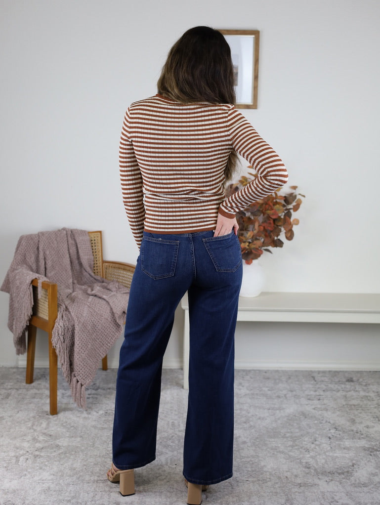 Back view of a person wearing a terracotta striped Mindy Ribbed Striped Top and dark blue wide-leg jeans.