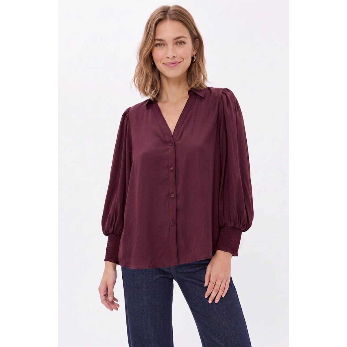 A woman wearing a Naked Zebra - Soft Billowy Sleeve Button Front Blouse: Wine / L, featuring a wine-colored button-front design with billowy sleeves and smocked cuffs.