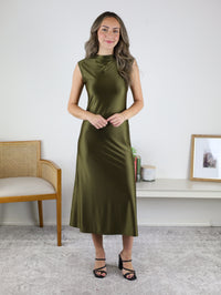 A woman wearing the olive green Desi Drape Neckline Maxi Dress with a high draped neckline and black heeled sandals, styled for a sophisticated holiday party.