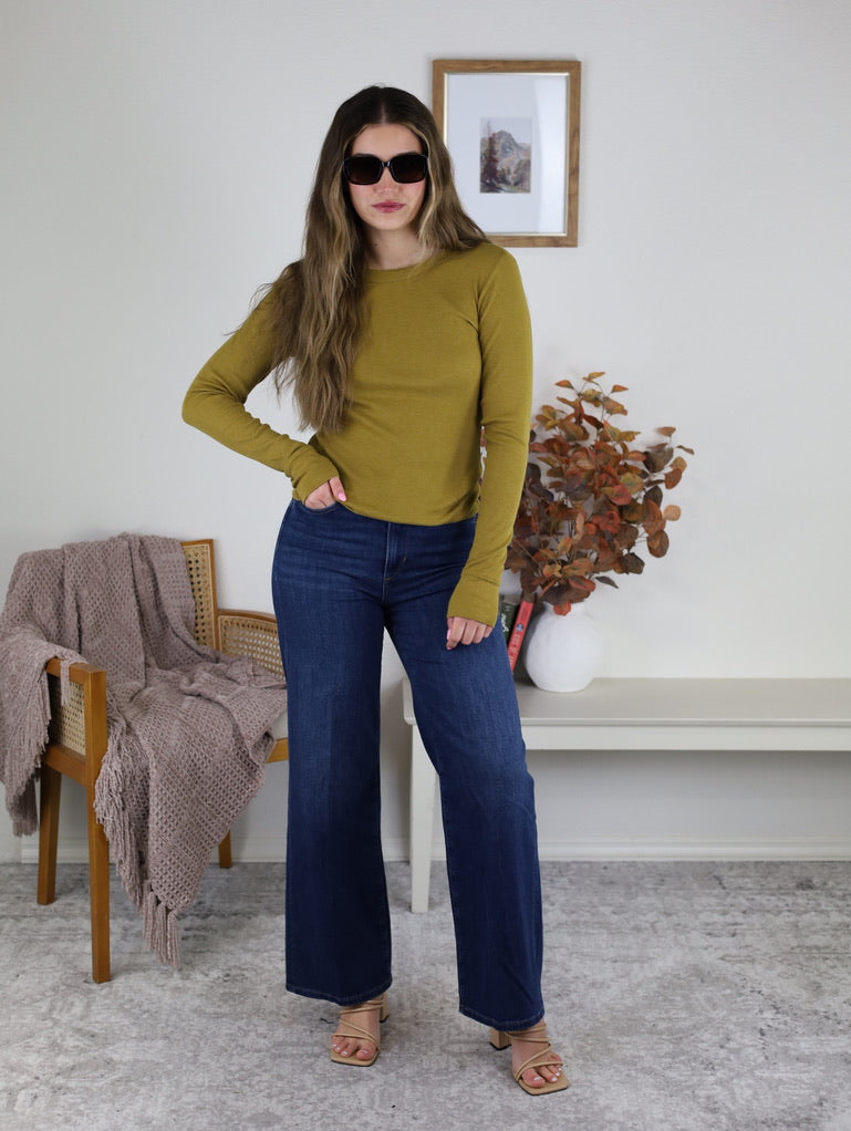 A person wearing a Dijon yellow Dee Ribbed Round Neck Tee, dark blue wide-leg jeans, and tan heeled sandals.