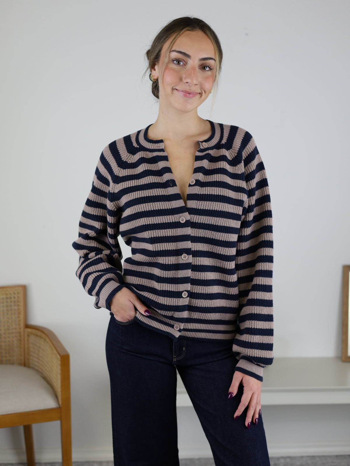 A person wearing the Justine Longsleeve Crewneck Striped Sweater, a button-front, long-sleeve design in dark navy and tan.