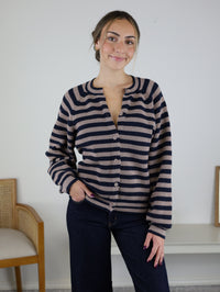 A person wearing the Justine Longsleeve Crewneck Striped Sweater, a button-front, long-sleeve design in dark navy and tan.