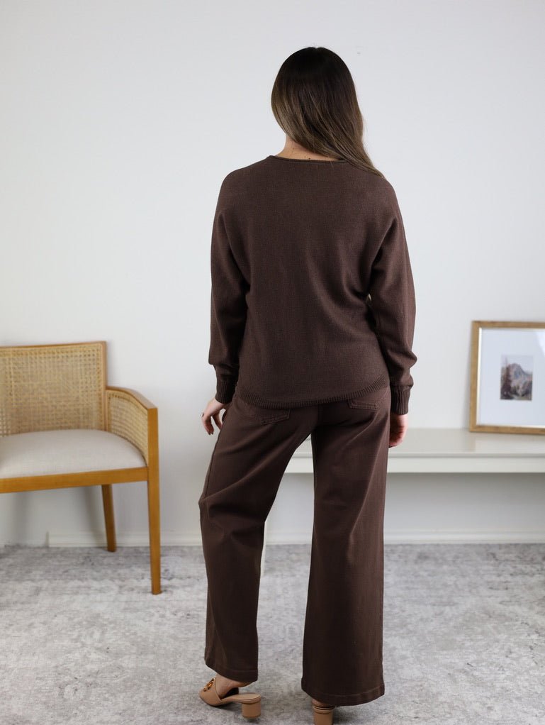 A person seen from behind, wearing an Eli Front Seam Sweater in a brown viscose-blend with a round neck and matching wide-leg trousers.