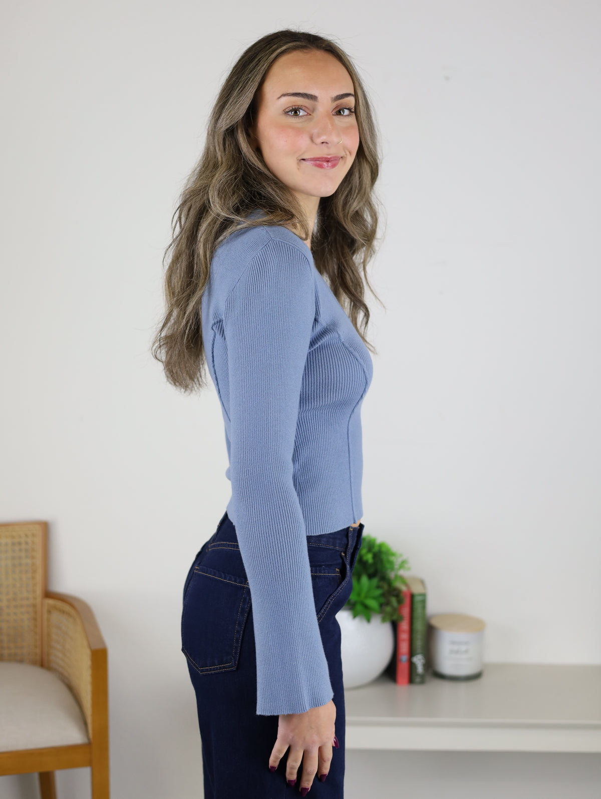A woman wears a periwinkle blue, fitted Luanne V-Neck Sweater and dark wash jeans.