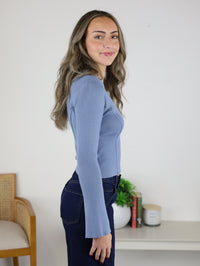 A woman wears a periwinkle blue, fitted Luanne V-Neck Sweater and dark wash jeans.