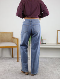 A person from behind wearing Sindra Mid Rise Sleek Tuxedo Sweatpant Jean mid-rise straight leg denim jeans with a dark side stripe.