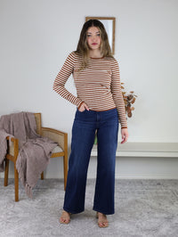Woman wearing a Mindy Ribbed Striped Top in terracotta stripes with long sleeves, paired with dark blue wide-leg jeans.