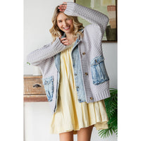 A smiling woman in a yellow dress and Veveret - Knit Body Denim Layerd Jacket: Cream / Denim / L poses indoors by a table and green plant, one arm raised and the other bent.
