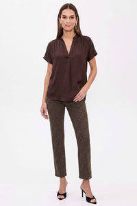 A woman wearing a Naked Zebra - Drop Shoulder Regular Blouse: Chocolate / L, a chocolate brown, drop-shoulder woven polyester blouse with a V-neck and animal-print trousers.