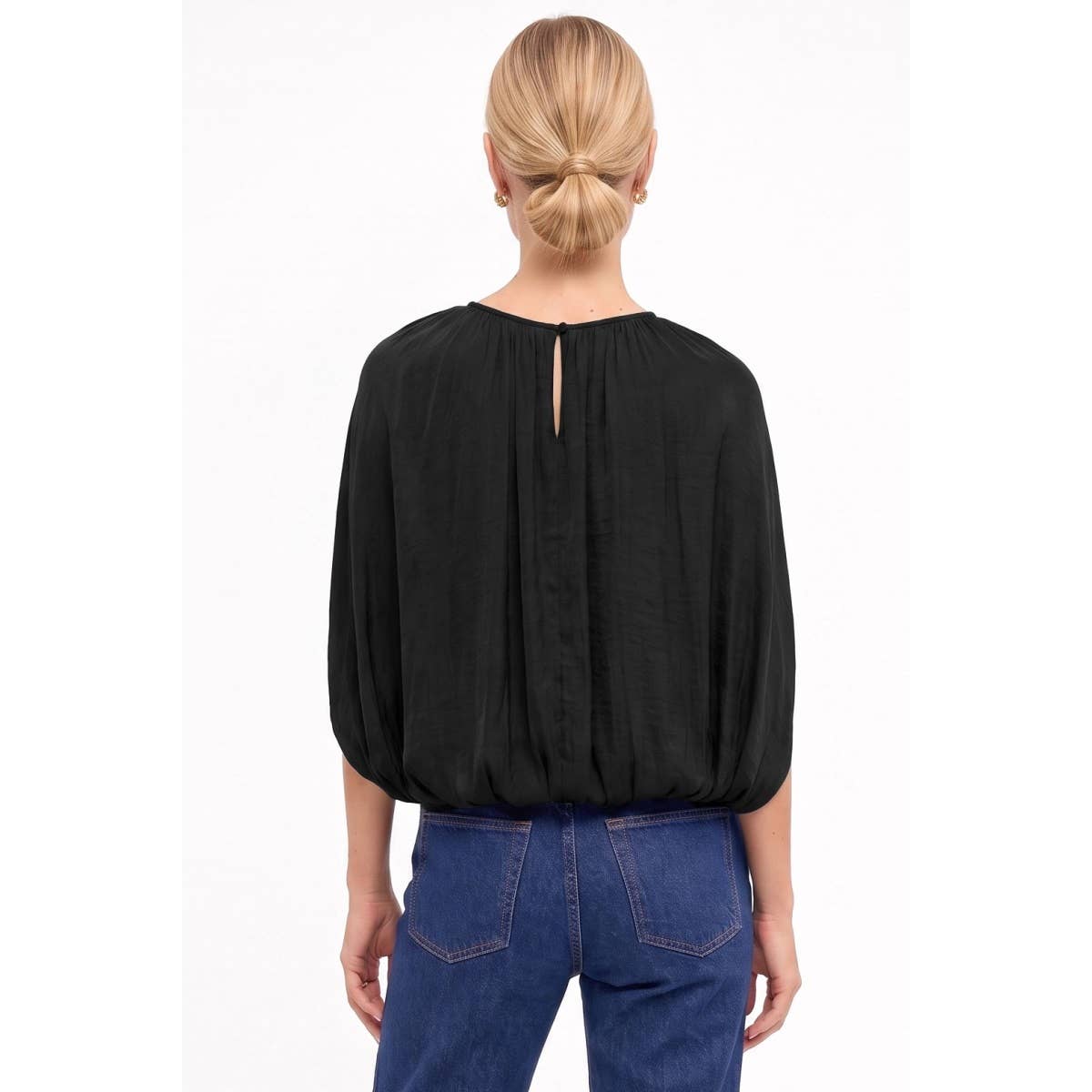 Back view of a Naked Zebra - Silky Draped Cape Sleeve Blouse: Wine / L in black with a gathered waistband and a small keyhole opening at the nape, worn with blue jeans.