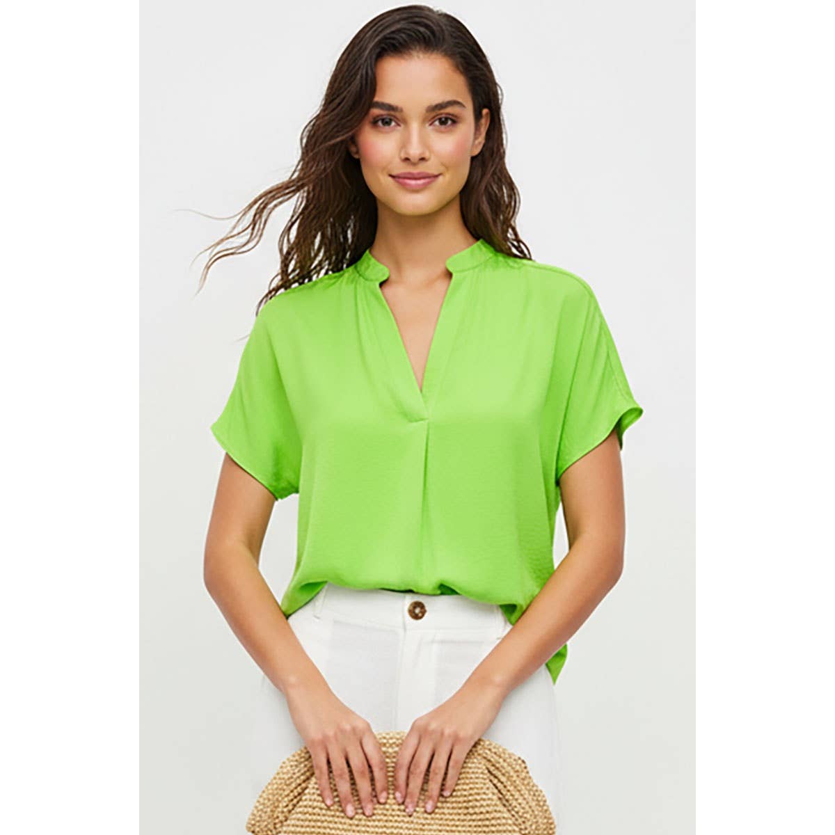 A woman wearing a lime green, drop shoulder V-neck Naked Zebra - Drop Shoulder Regular Blouse and white trousers.