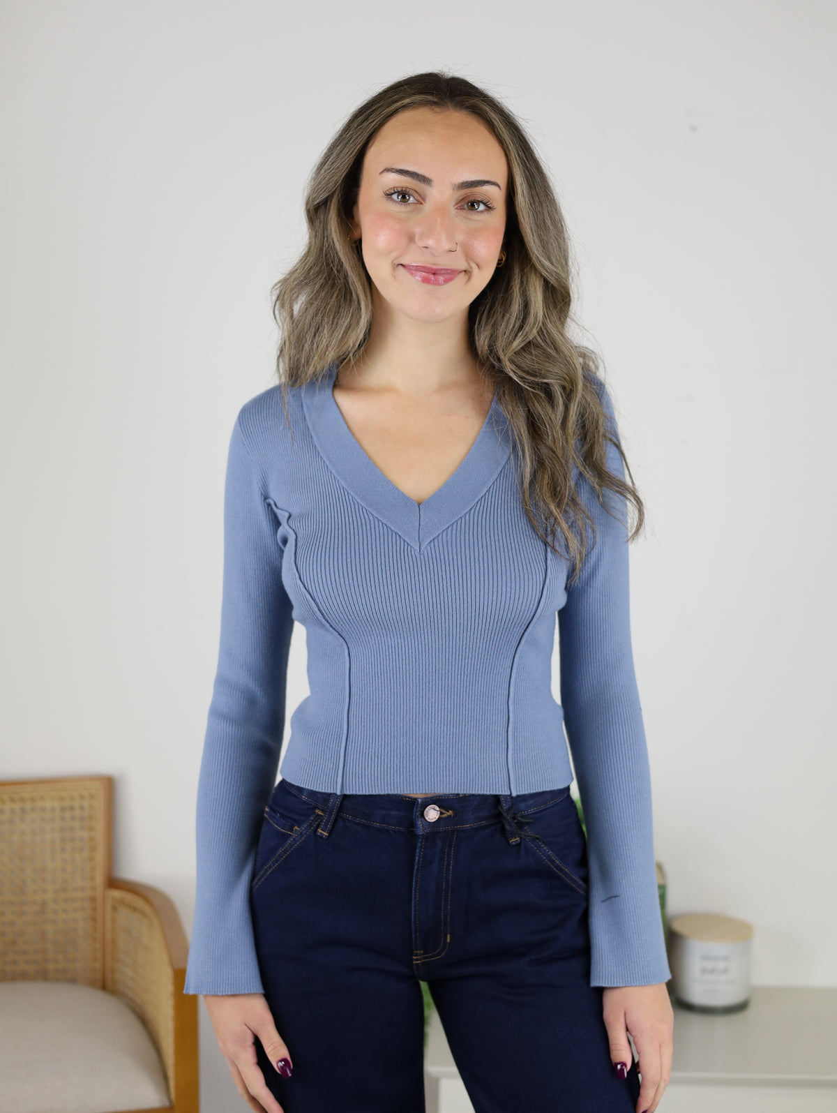 A woman wearing a dusty blue ribbed Luanne V-Neck Sweater with long sleeves.
