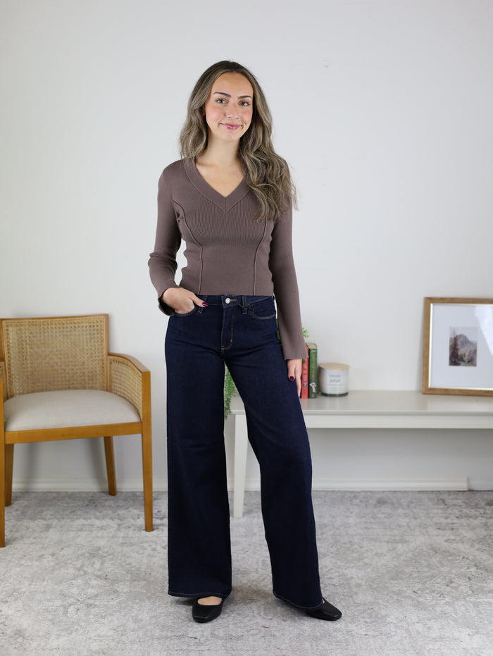 A woman wearing a Luanne V-Neck Sweater paired with dark blue wide-leg jeans.