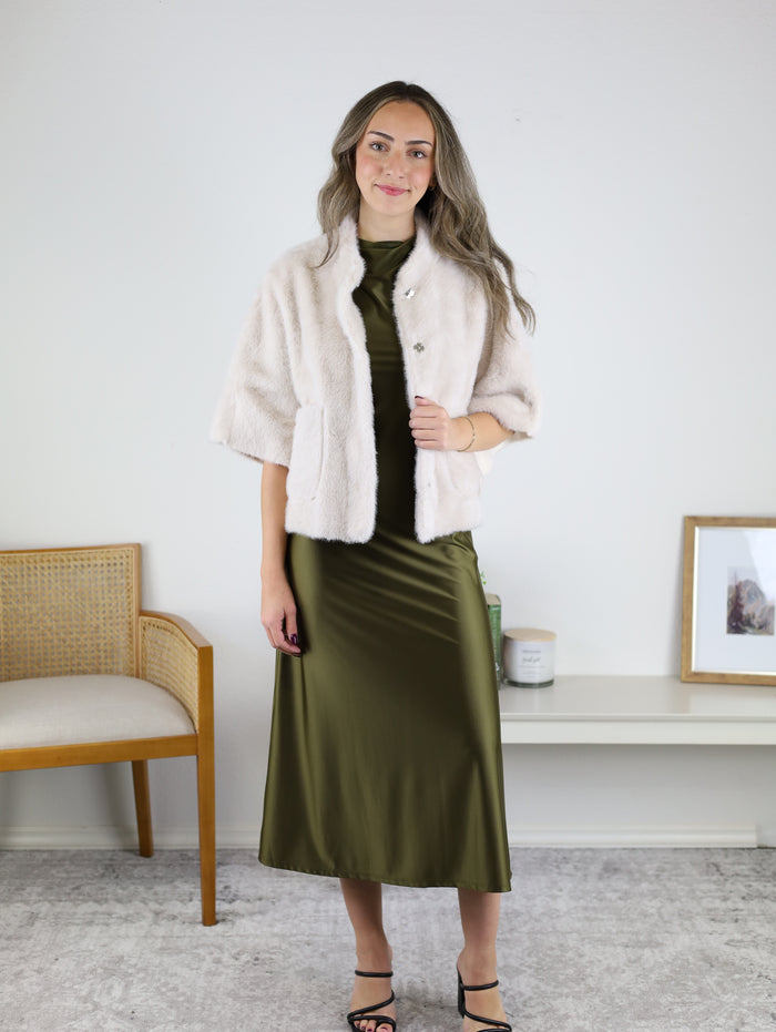 A person wearing a Jordan Fur Cape Sleeve Jacket over a sleeveless olive green midi dress.