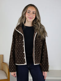 A person wearing a Reba Fleece Puffer Jacket, featuring a high-pile finish, a white-trimmed collar, and a button-front closure.