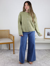 Woman wearing a lightweight, olive Olive Oversized Cardigan with a button-front and wide-leg blue jeans.