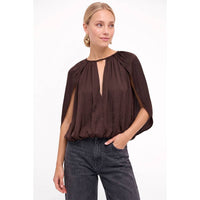 Naked Zebra - Silky Draped Cape Sleeve Blouse in wine, featuring a split neckline and draped cape sleeves, worn with gray jeans.
