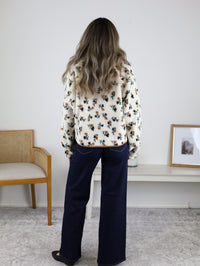 Back view of a person wearing a cream-colored Casin Floral Print Fluffy Fleece Jacket and wide-leg blue jeans.