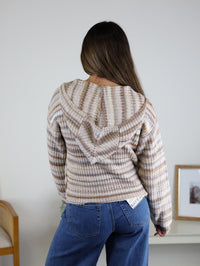 Back view of a person wearing a beige and brown striped Romy Hooded Cardigan Sweater and blue jeans.