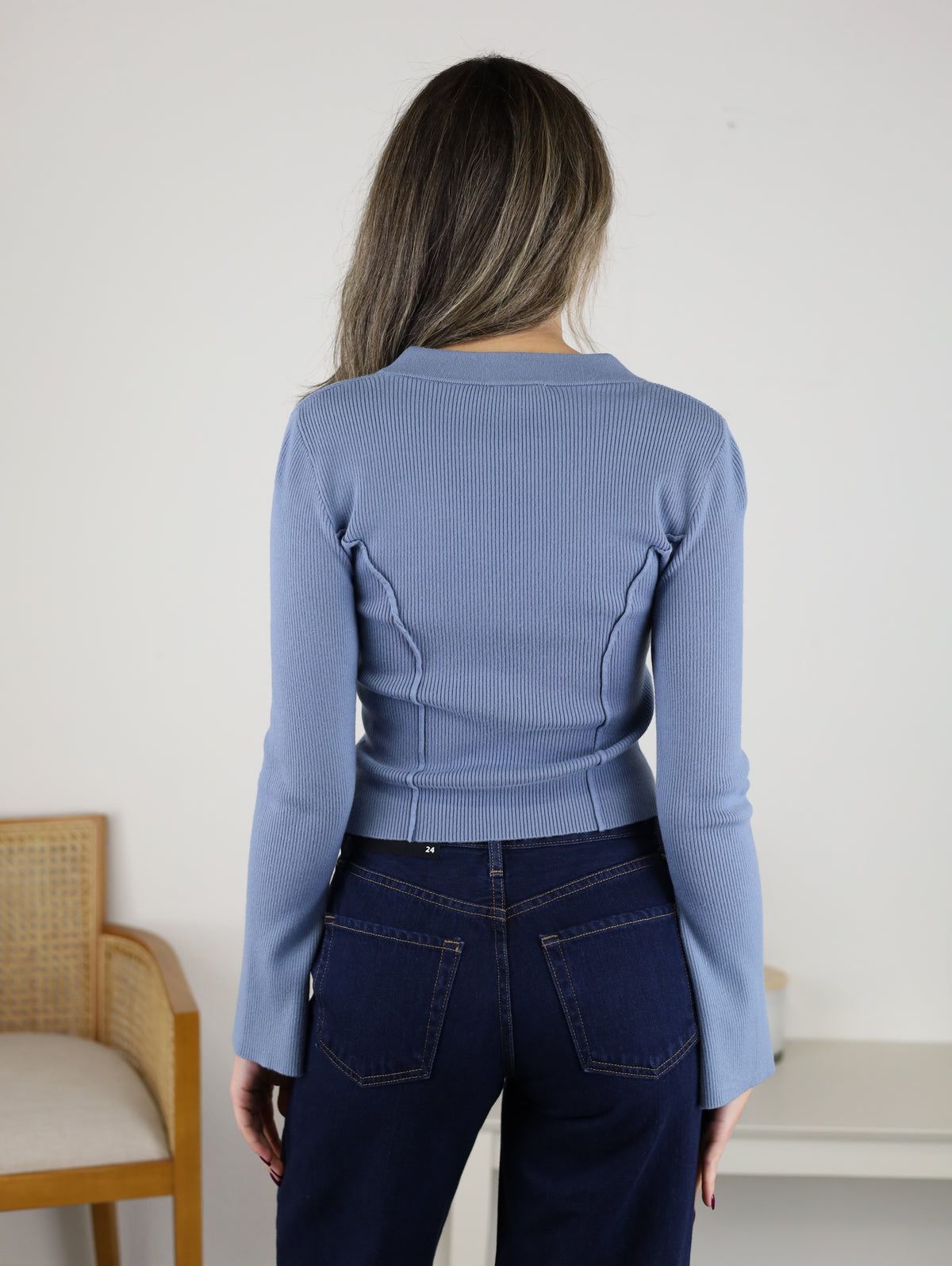 A person viewed from behind, wearing a long-sleeved, ribbed blue Luanne V-Neck Sweater.