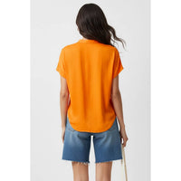 Back view of a person wearing a bright orange Naked Zebra - Drop Shoulder Regular Blouse: Chocolate / L and denim shorts.