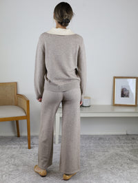 A person viewed from behind wearing a beige and cream Rebecca Sweater/Pant Set, featuring a long-sleeved sweater with a contrasting collar and matching wide-leg trousers.