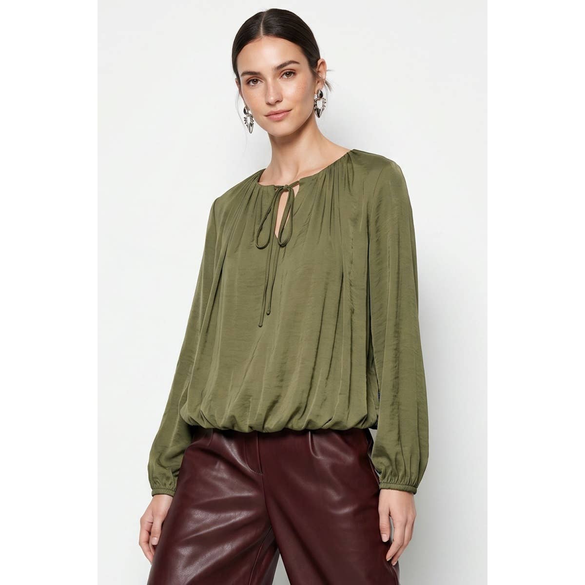 Olive green Naked Zebra - Long Sleeve Draped Bubble Hem Blouse: Wine / L with a drawstring neckline and a gathered bubble hem, worn with dark reddish-brown trousers.